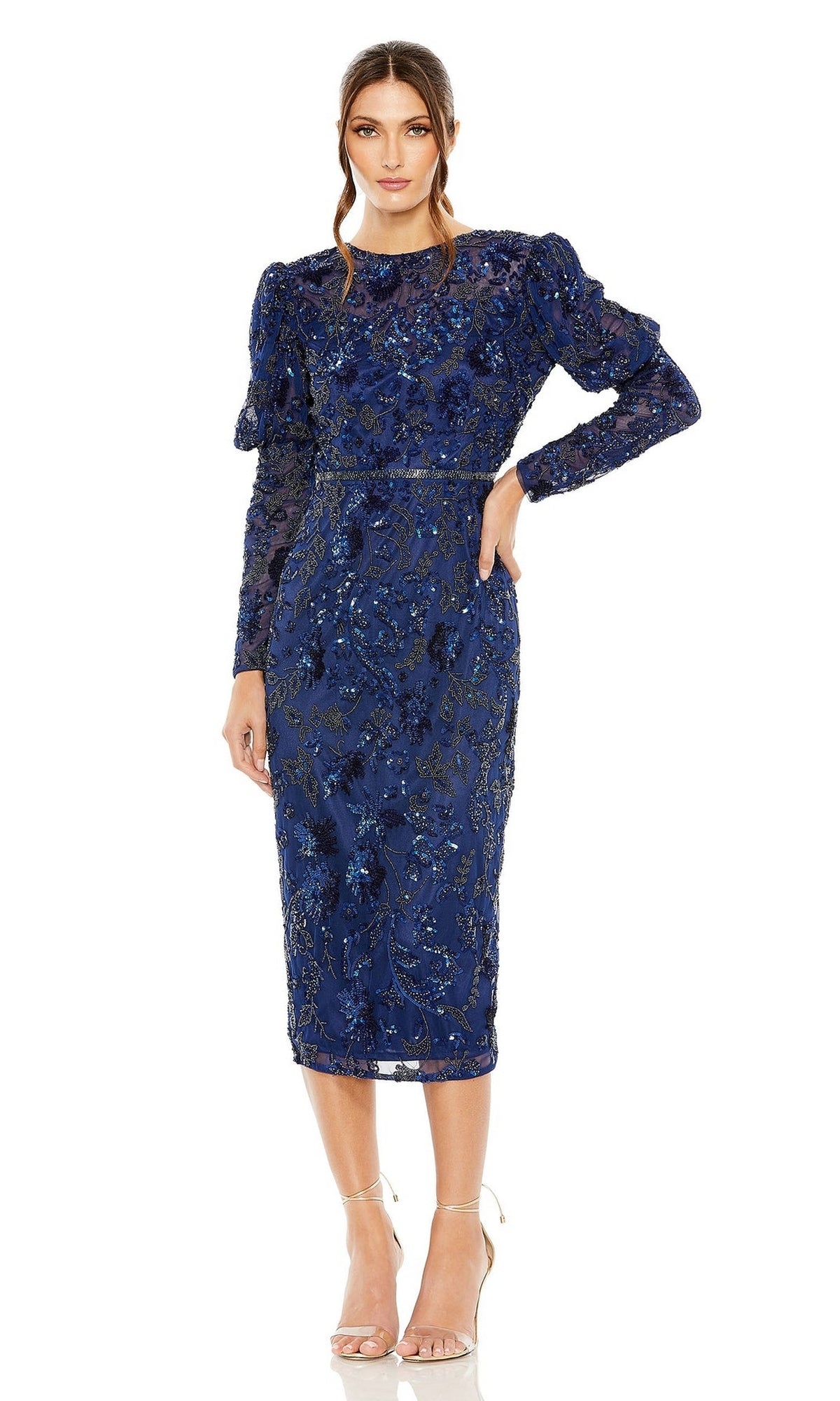 A woman in the Short Semi-Formal Dress 5590 by Mac Duggal, featuring blue long sleeves, intricate beading and embroidery, and a beaded waistband, stands in neutral heels against a white background.